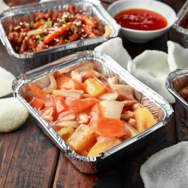 Çin yemeği paket servisi olan restoran. Gevrek parçalanmış sığır eti, tatlı ve ekşi tavuk kanatları, fasulye filizi, ananas, acı biber sosu ve karides kraker ile erişte yumurta