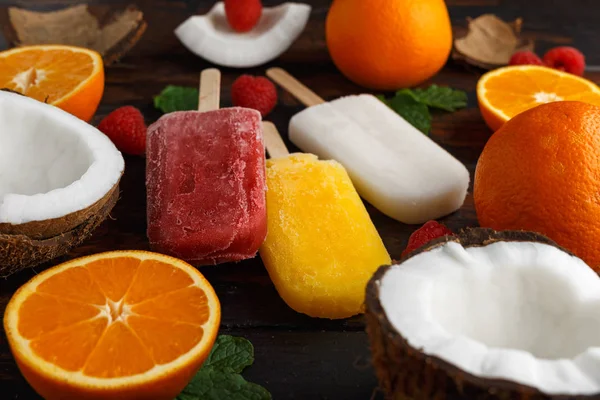 Coco casero, naranja, paletas de frambuesa, helado, sobre mesa de madera. Comida de verano . —  Fotos de Stock