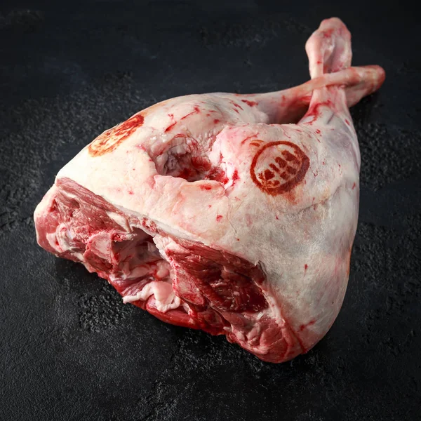 Jambe d'agneau crue sur table en pierre noire . — Photo