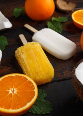 Ev yapımı Hindistan cevizi, turuncu çubuklu dondurmayı, ahşap masa üzerinde Buz lolly. Yaz gıda.