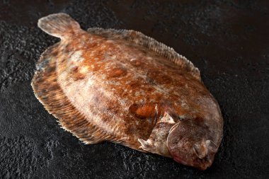 Raw lemon sole fish on black background, top view clipart