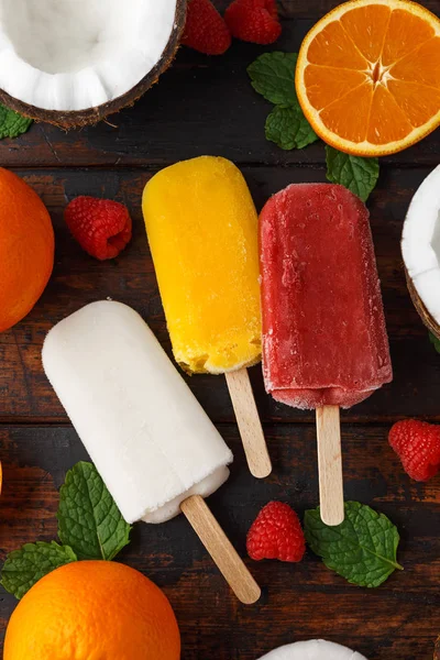 Coco casero, naranja, paletas de frambuesa, helado, sobre mesa de madera. Comida de verano . —  Fotos de Stock