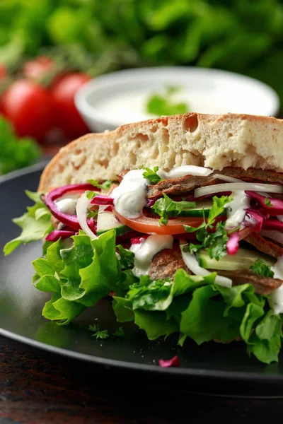 Doner kebab, mięso jagnięce smażone z warzywami i czosnek sos w Chleb turecki — Zdjęcie stockowe