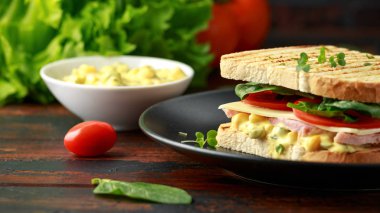 Jambon, peynir, domates, ıspanak, Mısır, mayonez, hardal, turşusu, kızarmış ekmek ve patates cipsi ile sandviç.