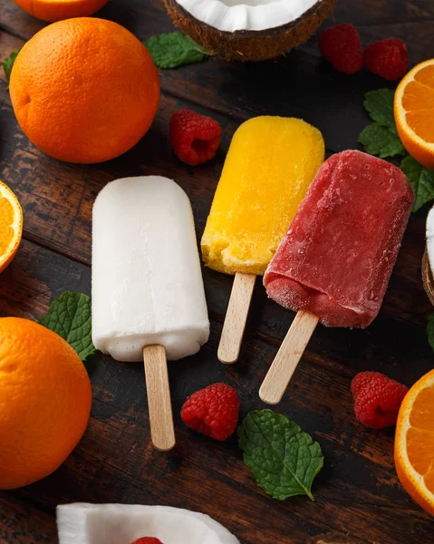 Coco casero, naranja, paletas de frambuesa, helado, sobre mesa de madera. Comida de verano . —  Fotos de Stock