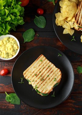 Jambon, peynir, domates, ıspanak, Mısır, mayonez, hardal, turşusu, kızarmış ekmek ve patates cipsi ile sandviç.