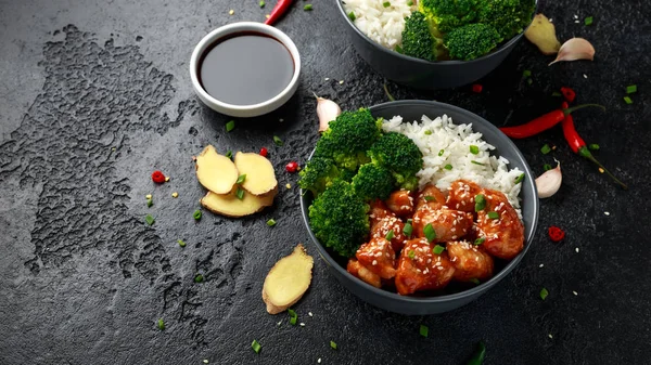 Teriyaki chicken, steamed broccoli and basmati rice served in two Asian clay bowls