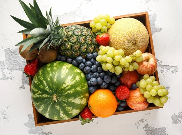 Różnorodność świeżych owoców i jagód w drewnianym pudełku. Zdrowe wegetariańskie letnie jedzenie. białe tło — Zdjęcie stockowe