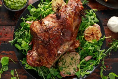 Nane sosu, biberiye ve sarımsak ile Rosto Kuzu bacak. siyah plaka üzerinde, ahşap masa