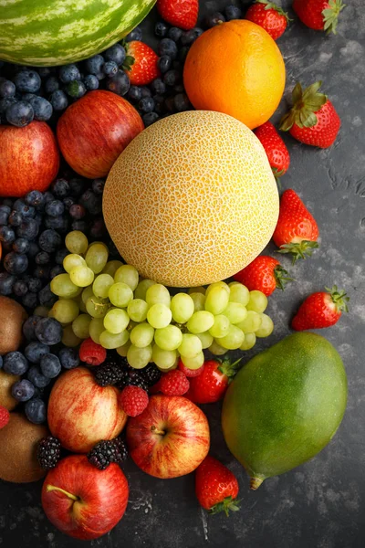 Variété de fruits frais et de baies sur fond sombre : cantaloup, melon, pastèque, myrtille, oranges, pomme, fraise, ananas, mangue, raisin et kiwi . — Photo