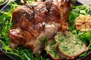 Nane sosu, biberiye ve sarımsak ile Rosto Kuzu bacak. siyah plaka üzerinde, ahşap masa