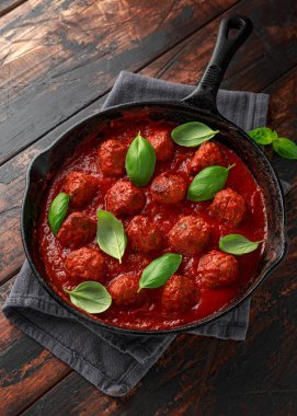 Tatlı ve sıcak domates sosu, fesleğen ile demir döküm Ev yapımı Köfte. Ahşap masa üzerinde
