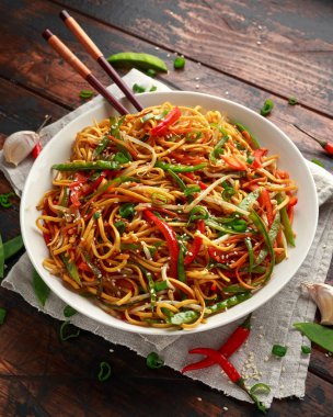 Chow mein, noodles and vegetables dish with wooden chopsticks clipart
