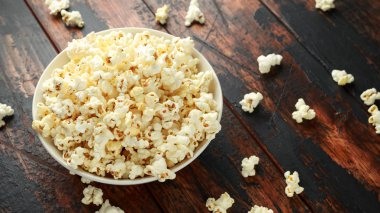 ahşap masa üzerinde tuzlu patlamış mısır kase