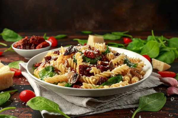 Fusilli pasta met zongedroogde tomaten, champignons, Parmezaanse kaas en spinazie. gezonde voeding. — Stockfoto