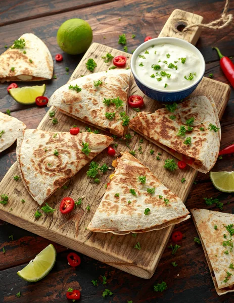 Mexican quesadilla with chicken, corn, black beans, cheese, vegetables, lime and yogurt sauce on wooden board — Stock Photo, Image