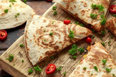 Ahşap tahta üzerinde tavuk, mısır, siyah fasulye, peynir, sebze, kireç ve yoğurt sos ile Meksika quesadilla