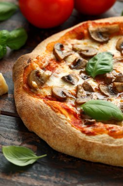 Ahşap masada fesleğen, domates, mozzarella ve parmesan peyniri ile Sıcak Mantar Pizza. yemeye hazır. vejetaryen gıda