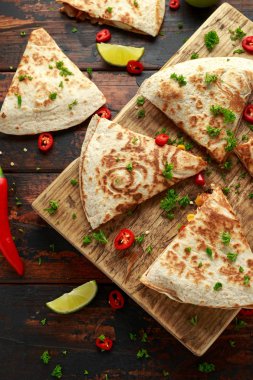 Ahşap tahta üzerinde tavuk, mısır, siyah fasulye, peynir, sebze, kireç ve yoğurt sos ile Meksika quesadilla