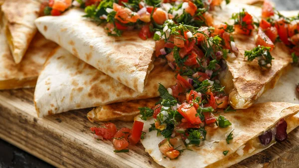 Tavuk ve peynir ile Meksika gıda quesadillas ev yapımı taze salsa tepesi ile rustik ahşap doğrama tahtası servis