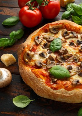 Ahşap masada fesleğen, domates, mozzarella ve parmesan peyniri ile Sıcak Mantar Pizza. yemeye hazır. vejetaryen gıda