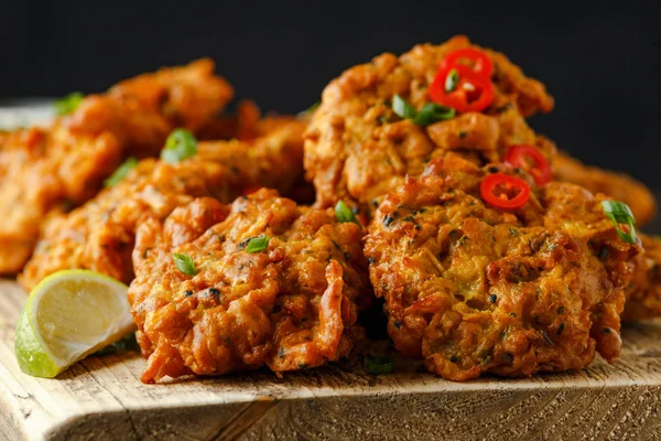 Indian takeaway food, spicy onion bhajis served with chili yoghurt dip and lime wedges on wooden board — Stock Photo, Image