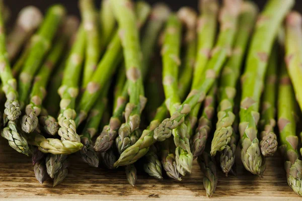 Freshly picked organic asparagus tips on wooden board — Stock Photo, Image
