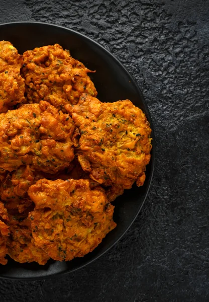 Indisches Essen zum Mitnehmen, würzige Zwiebelbhajis auf schwarzem Teller — Stockfoto