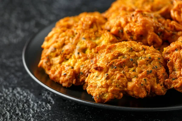 Indisches Essen zum Mitnehmen, würzige Zwiebelbhajis auf schwarzem Teller — Stockfoto