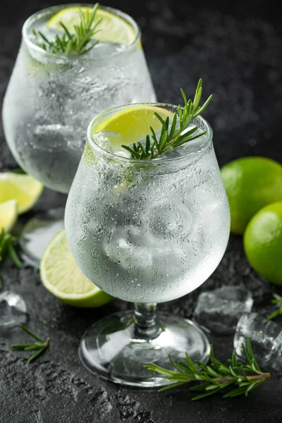 Gin and Tonic Bevanda alcolica con calce, rosmarino e ghiaccio sul tavolo nero rustico — Foto Stock