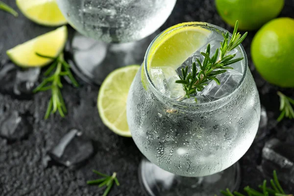 Gin and Tonic Bevanda alcolica con calce, rosmarino e ghiaccio sul tavolo nero rustico — Foto Stock