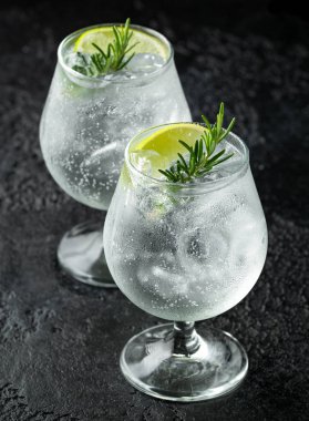 Cin ve Tonik Alkol rustik siyah masada Kireç, Biberiye ve buz ile içki