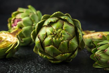 Koyu arka plan üzerinde taze ham organik olarak yetiştirilen enginar çiçek tomurcukları