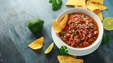 Limon, kırmızı soğan, jalapeno biber, maydanoz ve tortilla cips ile beyaz kapta Meksika Domates Salsa