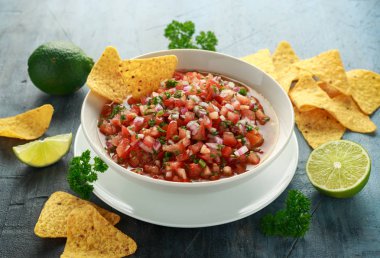 Limon, kırmızı soğan, jalapeno biber, maydanoz ve tortilla cips ile beyaz kapta Meksika Domates Salsa