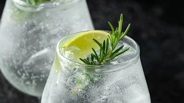 Gin i tonik alkohol pić z limonka, rozmaryn i lód na rustykalny czarny stół — Zdjęcie stockowe