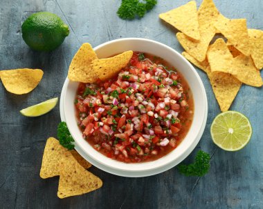 Limon, kırmızı soğan, jalapeno biber, maydanoz ve tortilla cips ile beyaz kapta Meksika Domates Salsa