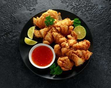 Siyah plaka üzerinde Biber sos ve kireç ile Kızarmış Bloomin Soğan