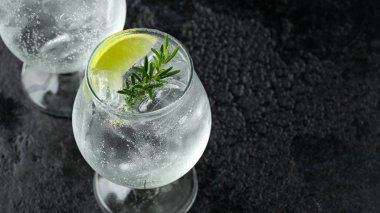 Cin ve Tonik Alkol rustik siyah masada Kireç, Biberiye ve buz ile içki