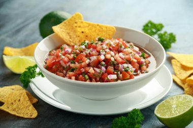 Limon, kırmızı soğan, jalapeno biber, maydanoz ve tortilla cips ile beyaz kapta Meksika Domates Salsa