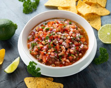 Limon, kırmızı soğan, jalapeno biber, maydanoz ve tortilla cips ile beyaz kapta Meksika Domates Salsa