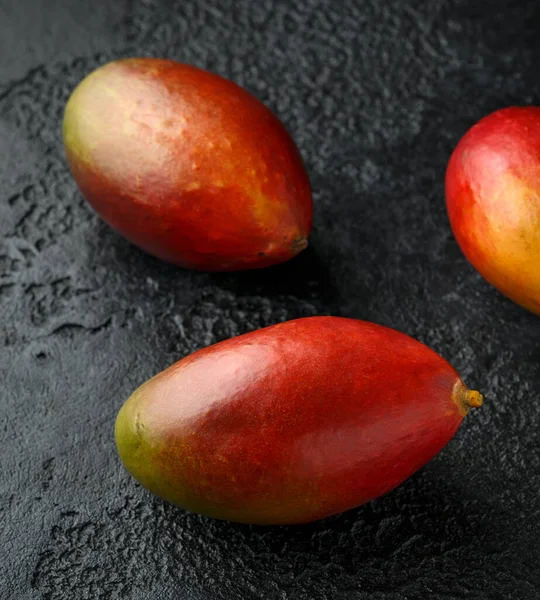 Свежие тропические фрукты манго на деревенском черном фоне — стоковое фото