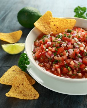 Limon, kırmızı soğan, jalapeno biber, maydanoz ve tortilla cips ile beyaz kapta Meksika Domates Salsa
