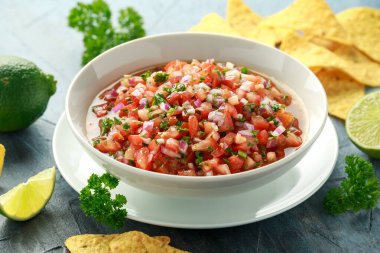 Limon, kırmızı soğan, jalapeno biber, maydanoz ve tortilla cips ile beyaz kapta Meksika Domates Salsa