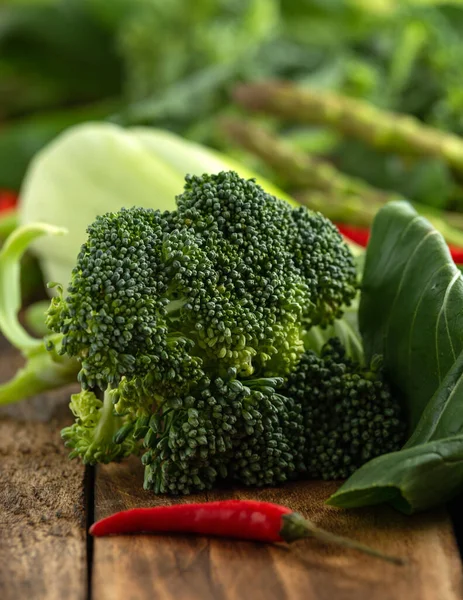 Variedad de verduras verdes pak choi, espárragos, brócoli y aves chile en la mesa rústica de madera —  Fotos de Stock