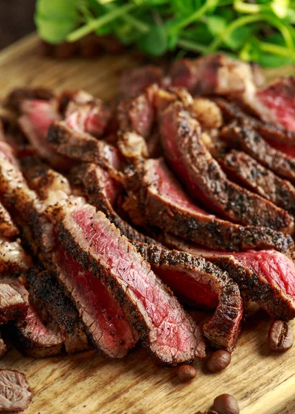Freshly cooked seasoned with home made coffee rub sliced beef steak served on wooden board with green salad — Stock Photo, Image