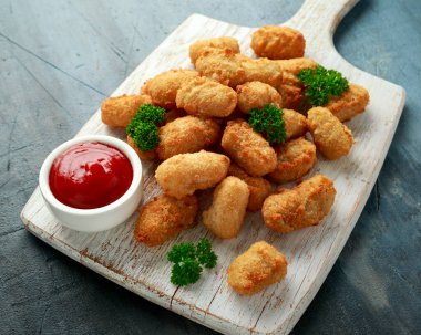 Beyaz tahta üzerinde ketçaplı çıtır çıtır karides nuggetları..