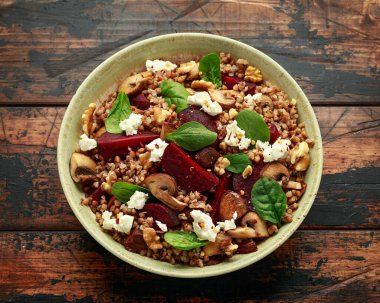 Mantarlı karabuğday ve pancar salatası, ceviz, ıspanak ve kırsal ahşap masada beyaz peynir. sağlıklı diyet yemekleri.