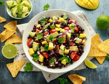 Avokado, siyah fasulyeli mango salatası, domates, kırmızı soğan ve tortilla cipsi. sağlıklı yiyecekler