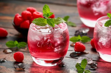 Ahududu kokteylini buz ve nane şekeri ile ahşap masada tazeliyorum.